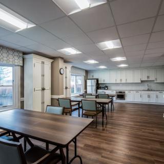 A modern kitchen and dining area featuring tables, chairs, appliances, and hardwood flooring.