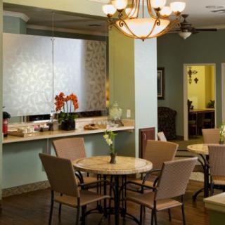 A cozy dining area with several tables and chairs, elegantly lit by a chandelier.