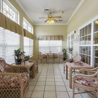 A cozy sunroom filled with natural light, showcasing wicker furniture and potted plants.