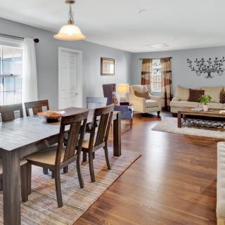 A spacious open-plan dining and living room with hardwood floors, well-arranged furniture, and bright lighting.