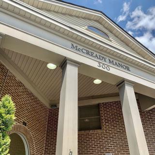 The entrance of McCrary Manor with prominent columns and brickwork set against a blue sky.