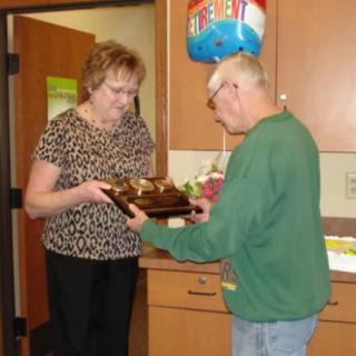Two people celebrate a birthday with cupcakes and a festive balloon in a kitchen setting.