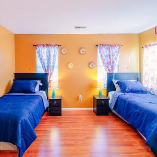 A cozy bedroom with twin beds, vibrant orange walls, and blue bedding.