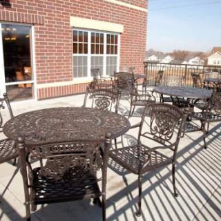 A cozy outdoor seating area featuring intricate metal tables and chairs, perfect for enjoying a meal in the sunshine.
