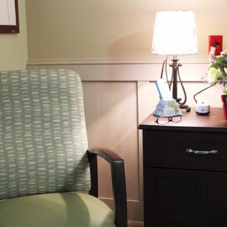 A cozy indoor setting featuring a green patterned chair and a small lamp-lit table.