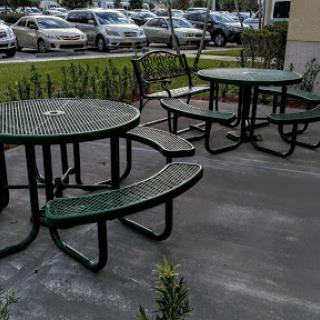 A set of green outdoor tables and benches arranged in a casual seating area.