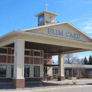 The entrance of a care facility with prominent signage and a cross on the roof.