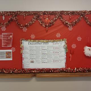 A festive bulletin board decorated with holiday-themed elements and information.