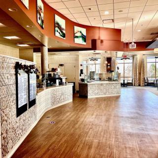 A modern and spacious cafe interior with a wooden floor and stylish counter.