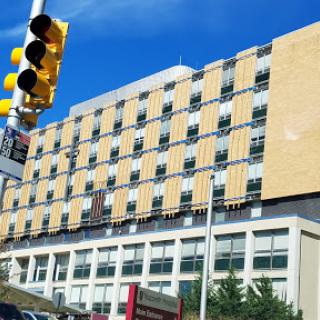 A modern building featuring distinctive wooden paneling and large windows, set against a clear blue sky.