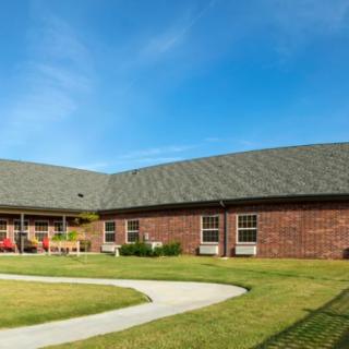 A single-story brick building with a sloped roof and well-maintained lawn under a clear blue sky.