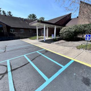 A view of the entrance to a building, featuring a well-defined parking area with accessible spots.