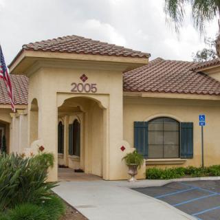 A beige building with an archway entrance, displaying the number 2006 and an American flag nearby.