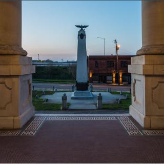 A view of a monument framed by architectural columns during sunset.
