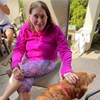 A woman enjoying a sunny day outdoors with her golden retriever by her side.