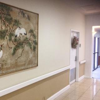 A well-lit hallway featuring a decorative painting on the wall.