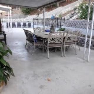 A covered outdoor patio with a dining table set and plants.