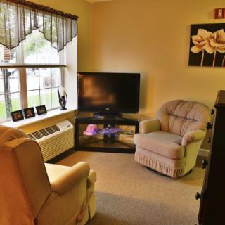 A cozy living room with two comfortable chairs, a TV, and a large window letting in natural light.