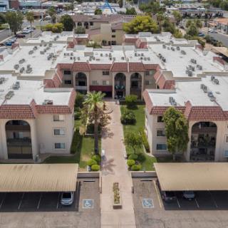 Aerial view of a well-maintained apartment complex featuring landscaped grounds and organized parking.