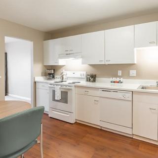 A modern kitchen interior with white cabinets and wooden flooring.