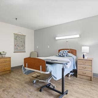 A well-lit hospital patient room featuring essential furniture and a comfortable bed.