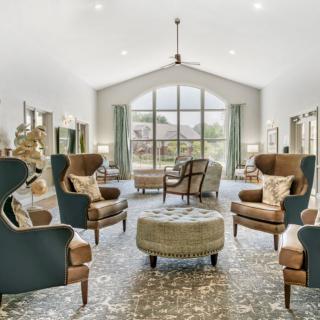 A spacious, elegantly designed living room featuring armchairs and a large window with natural light.