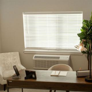 A tidy office space with a desk, chair, and window blinds.