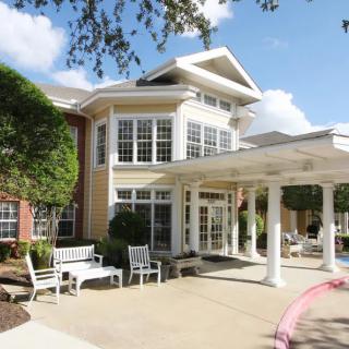 A sunny exterior view of a residential building with benches and landscaping.