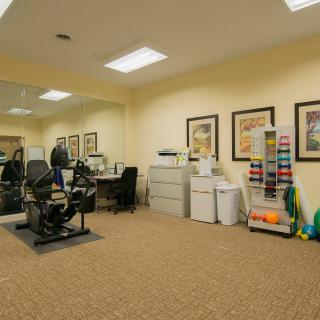 A physical therapy clinic with exercise equipment and office area.