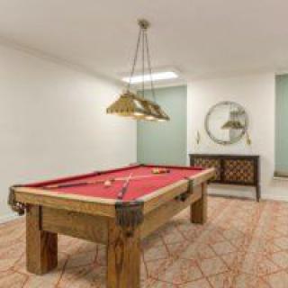 A recreation room featuring a red cloth pool table and stylish decor.