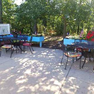 A peaceful outdoor patio area with tables and chairs under the shade of trees.