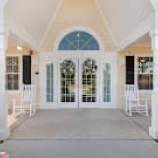 A welcoming front porch with double doors, rocking chairs, and an arched window.