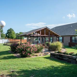 A well-maintained backyard with a patio and landscaped garden, featuring a lawn and various plants.