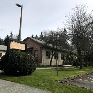 A view of a building surrounded by greenery and trees, with a sign visible in front.