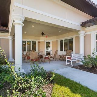 A cozy covered patio with outdoor seating and landscaping.