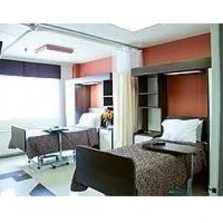 A modern hospital room with two patient beds separated by a curtain.