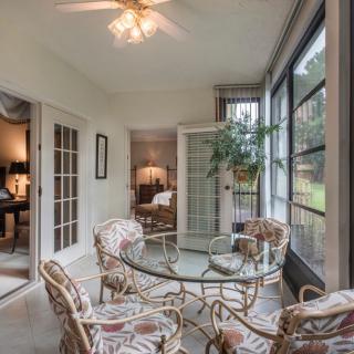 A cozy sunroom with a glass table, chairs, and ample natural light streaming through large windows.
