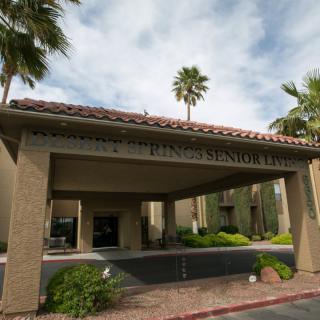 Entrance of a building with palm trees and landscaped surroundings.