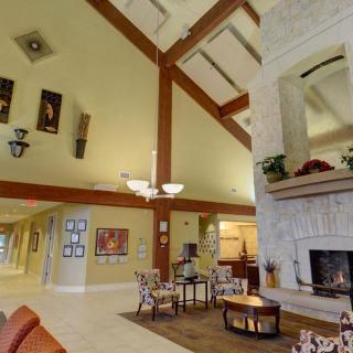 A spacious lobby with a high ceiling, featuring a large fireplace, seating area, and decorative art on the walls.