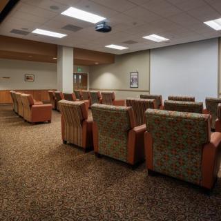 A comfortable seating area with plush chairs facing a projector screen, suitable for meetings or presentations.