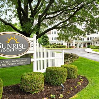 Entrance to a well-maintained retirement community with lush landscaping and a welcoming sign.