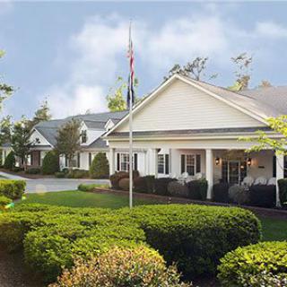 A residential building with manicured landscaping and a flagpole under a blue sky.