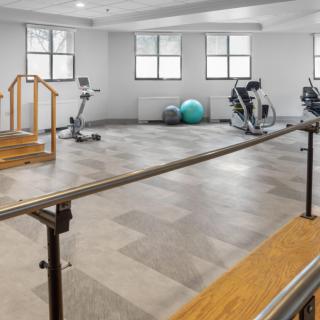 A fitness room with various exercise equipment, including a treadmill and stationary bike, designed for training and rehabilitation.