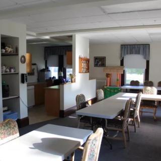 A community dining area with tables and chairs, connected to a kitchen space.
