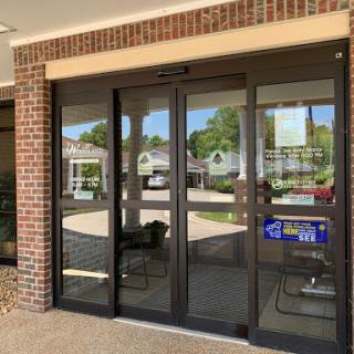 The entrance of a commercial building featuring glass doors with a brick facade.