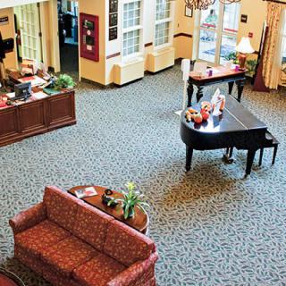 A spacious lobby with a grand piano, upholstered sofa, and elegant furnishings.