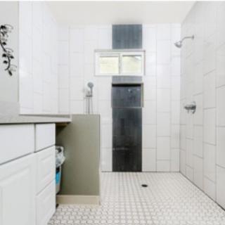 A modern, minimalist bathroom with white tiles and a spacious shower area.