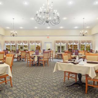 A spacious dining room with elegantly set tables and a large chandelier.