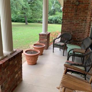 A cozy porch with seating and planters overlooking a lush green lawn.