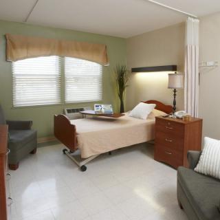 A hospital room with a bed and comfortable seating.
